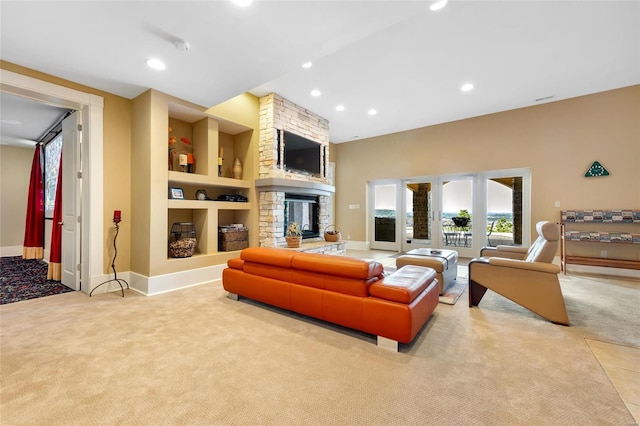 living room with built in shelves, a stone fireplace, and light carpet