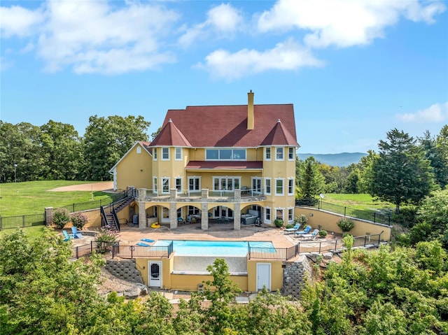 rear view of property with a yard, a fenced in pool, and a patio area