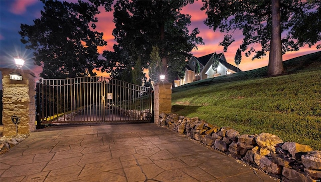 gate at dusk featuring a lawn