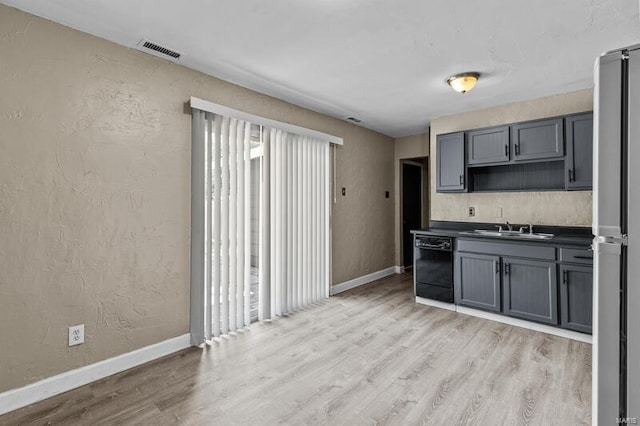 kitchen featuring light wood-type flooring, sink, black dishwasher, gray cabinets, and stainless steel refrigerator