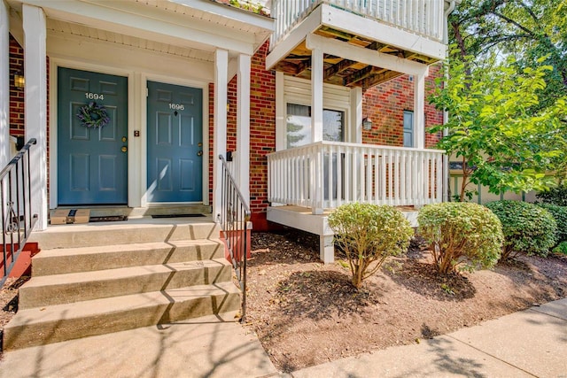 entrance to property with covered porch and brick siding