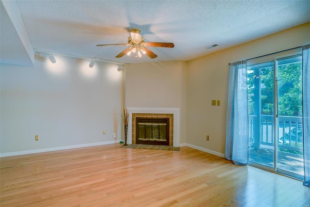 unfurnished living room featuring a textured ceiling, a fireplace, visible vents, baseboards, and light wood-type flooring