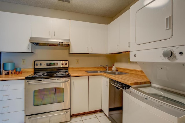 kitchen featuring stacked washer and clothes dryer, sink, black dishwasher, light tile patterned flooring, and stainless steel range with electric cooktop