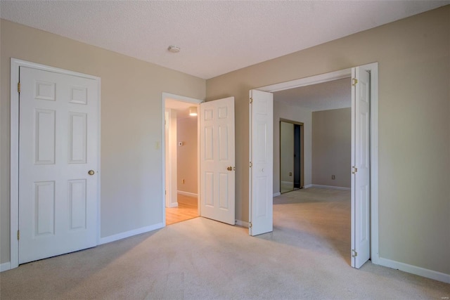 unfurnished bedroom featuring a textured ceiling, light colored carpet, and a closet