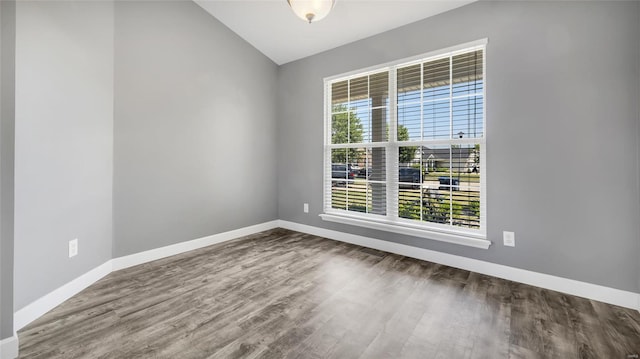 empty room with wood-type flooring and vaulted ceiling