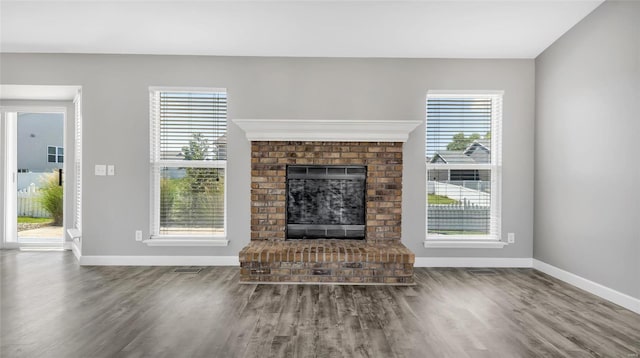 unfurnished living room with wood-type flooring and a brick fireplace