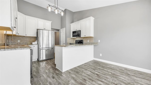 kitchen with stove, white cabinets, sink, hanging light fixtures, and stainless steel fridge