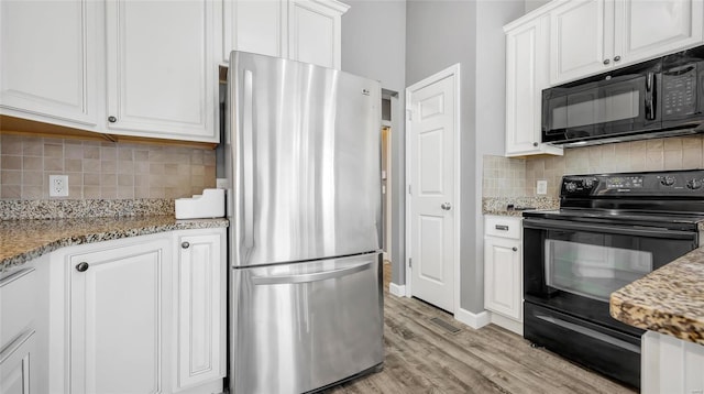 kitchen with decorative backsplash, light stone countertops, light wood-type flooring, black appliances, and white cabinets