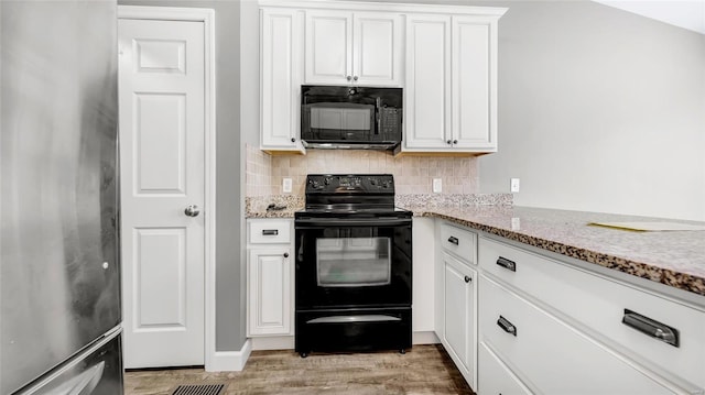 kitchen featuring white cabinetry, black appliances, light stone counters, and light wood-type flooring