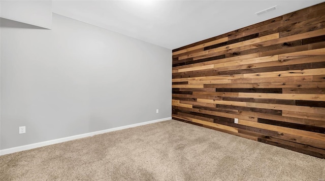 carpeted empty room featuring wooden walls