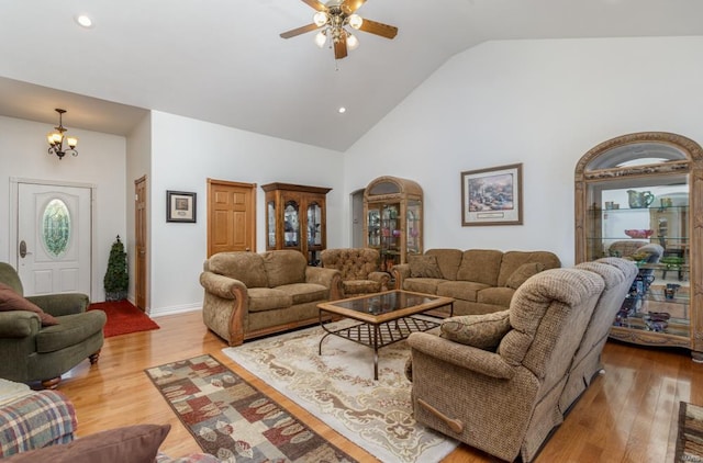 living room featuring ceiling fan with notable chandelier, high vaulted ceiling, and light hardwood / wood-style floors