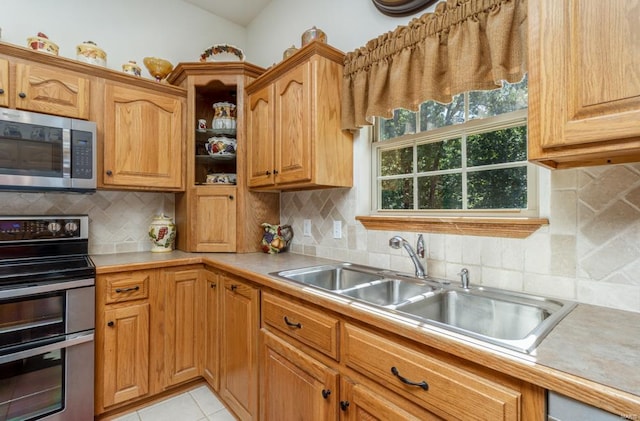 kitchen featuring sink, backsplash, stainless steel appliances, and light tile patterned flooring