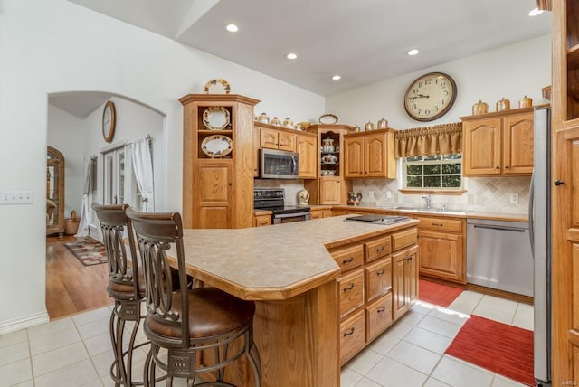 kitchen with a center island, light tile patterned floors, stainless steel appliances, and a kitchen bar