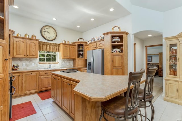 kitchen with light tile patterned floors, a kitchen breakfast bar, a kitchen island, decorative backsplash, and appliances with stainless steel finishes