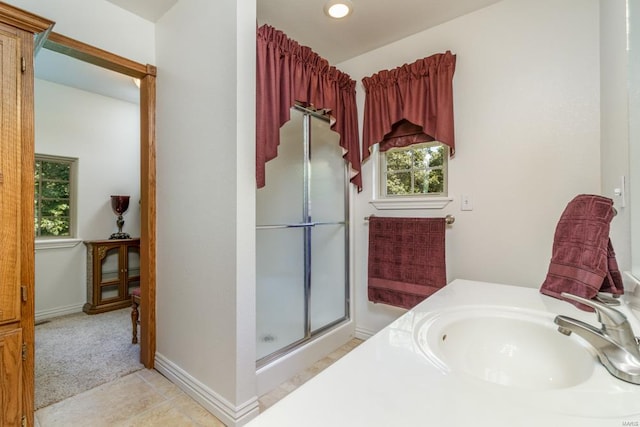 bathroom featuring a shower with shower door, vanity, and tile patterned floors