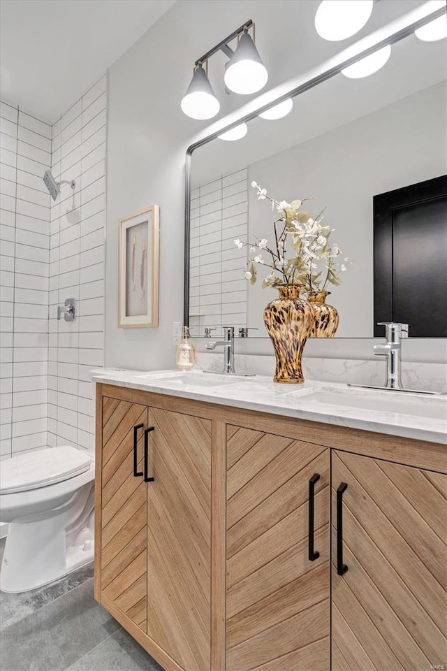 bathroom with vanity, toilet, and tiled shower