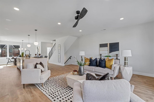 living room with ceiling fan, sink, and light wood-type flooring