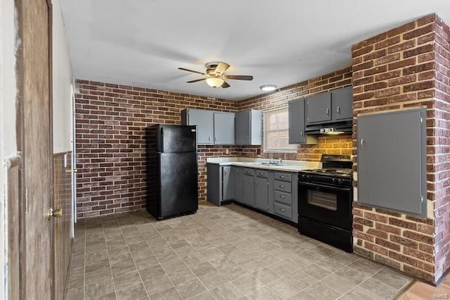 kitchen featuring ceiling fan, sink, brick wall, gray cabinets, and black appliances