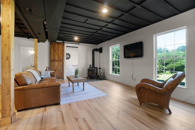 living room with a wealth of natural light, light hardwood / wood-style flooring, and a wood stove