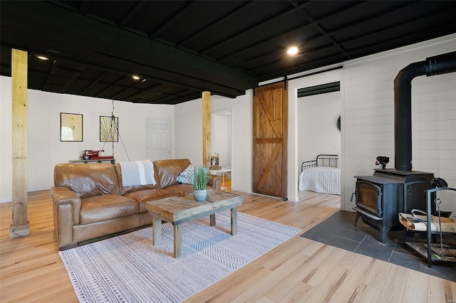 living room with hardwood / wood-style flooring, a barn door, and a wood stove