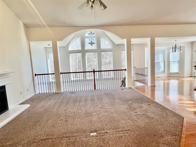 unfurnished living room featuring ceiling fan with notable chandelier and light hardwood / wood-style flooring