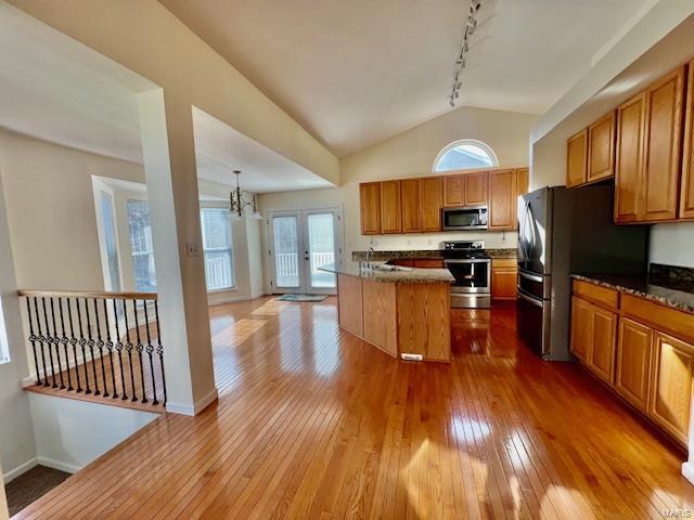 kitchen featuring stainless steel appliances, hardwood / wood-style flooring, a center island, and dark stone countertops