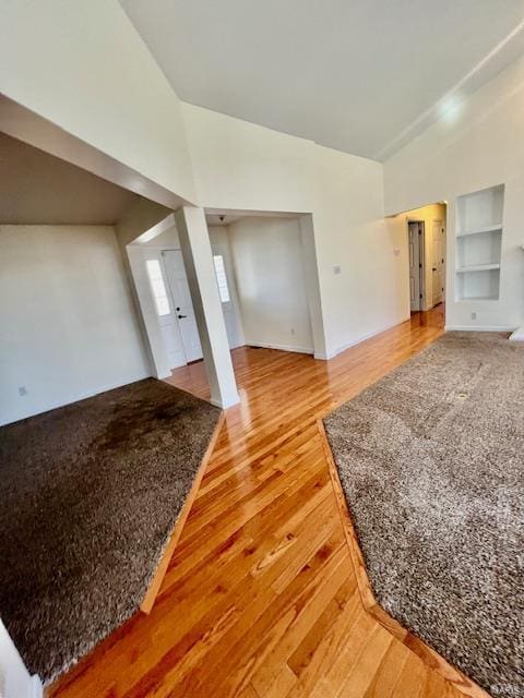 interior space with hardwood / wood-style flooring, high vaulted ceiling, and built in features