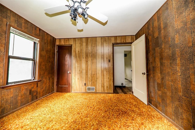 spare room featuring ceiling fan and wood walls