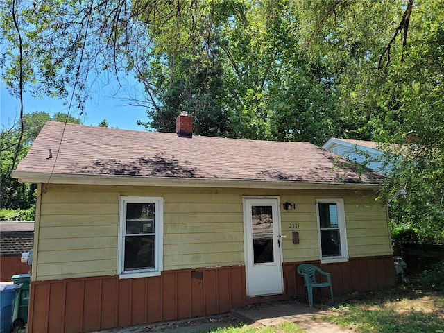 view of front facade featuring a shingled roof and a chimney