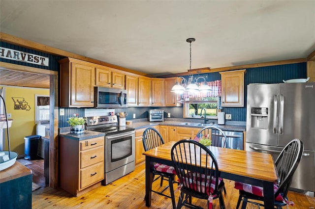 kitchen featuring sink, light hardwood / wood-style flooring, decorative light fixtures, and appliances with stainless steel finishes