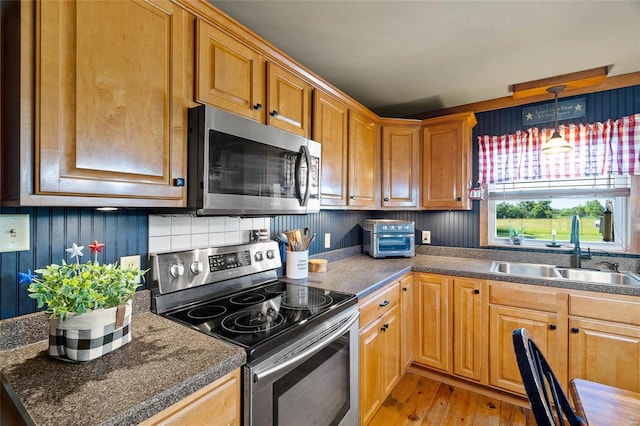 kitchen featuring hanging light fixtures, sink, light wood-type flooring, and appliances with stainless steel finishes