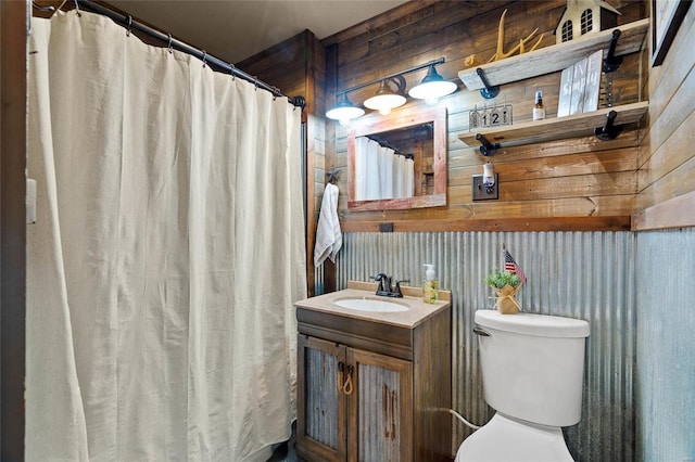 bathroom featuring wooden walls, vanity, and toilet