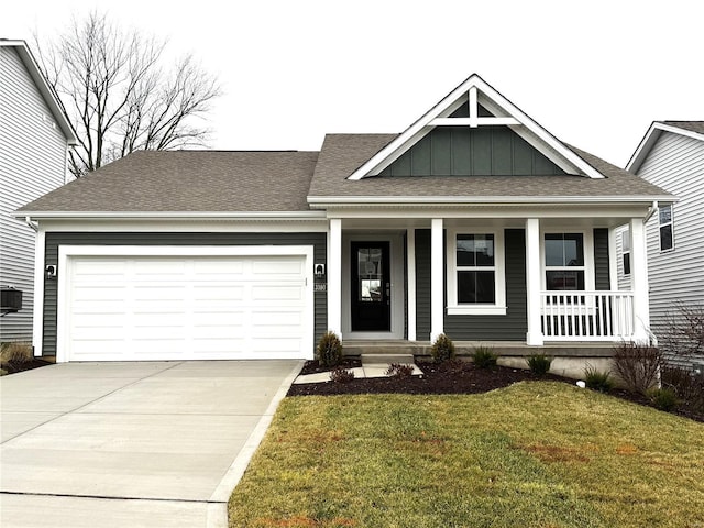 view of front facade with a shingled roof, an attached garage, board and batten siding, a front yard, and driveway