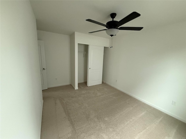 unfurnished bedroom with ceiling fan, baseboards, a closet, and light colored carpet