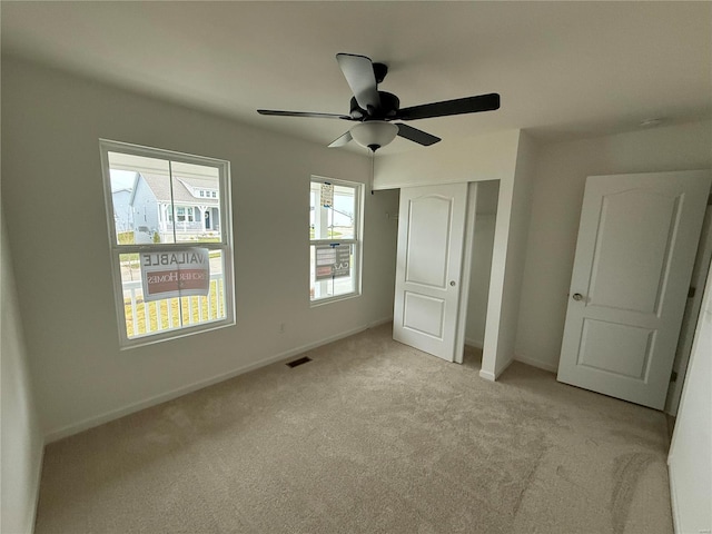 unfurnished bedroom featuring light colored carpet, a ceiling fan, baseboards, visible vents, and a closet