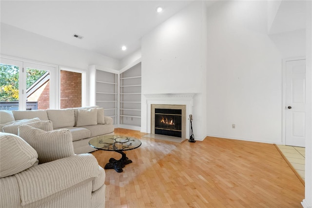 living room featuring a towering ceiling, hardwood / wood-style floors, and built in features