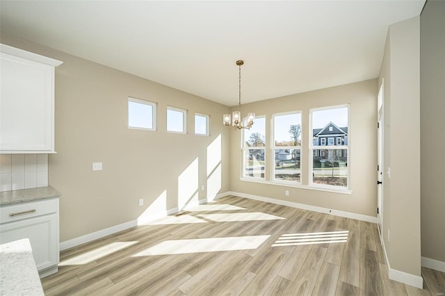 unfurnished dining area featuring an inviting chandelier and light wood-type flooring