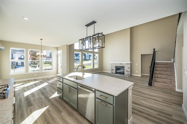 kitchen with hanging light fixtures, sink, a fireplace, appliances with stainless steel finishes, and dark hardwood / wood-style flooring