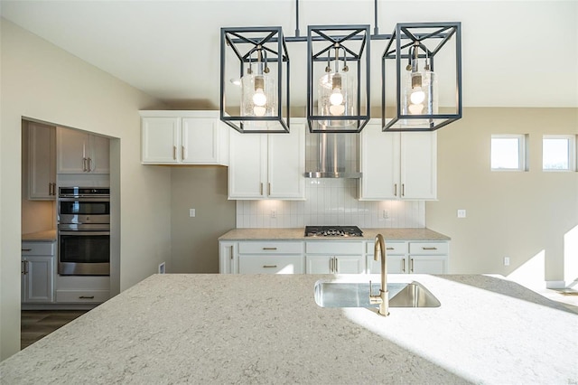 kitchen featuring tasteful backsplash, light stone counters, stainless steel appliances, sink, and white cabinets