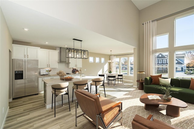 kitchen with white cabinetry, stainless steel refrigerator with ice dispenser, a chandelier, decorative light fixtures, and light wood-type flooring