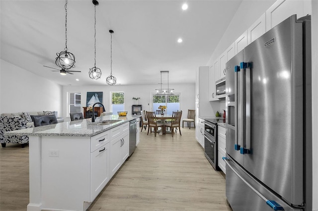 kitchen with stainless steel appliances, sink, white cabinets, and decorative light fixtures