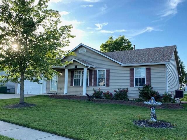 view of front of property featuring cooling unit, a front yard, and a garage