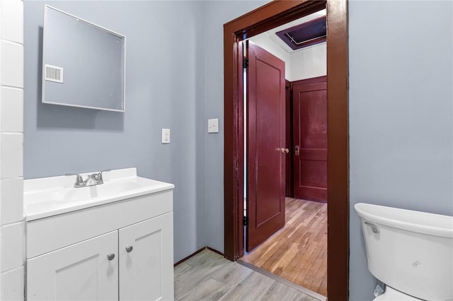 bathroom with toilet, hardwood / wood-style flooring, and vanity