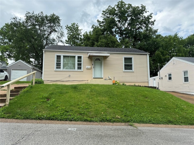 view of front of home featuring a garage, an outbuilding, and a front lawn