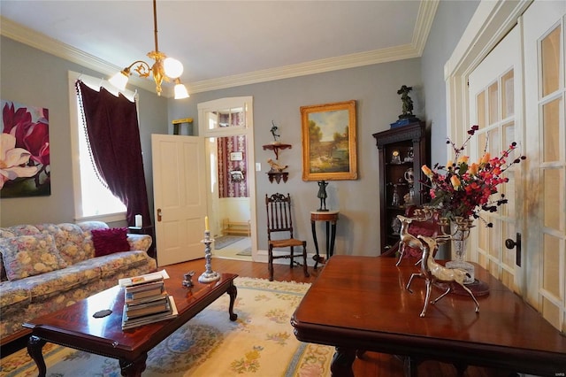 living room featuring wood-type flooring, a notable chandelier, and crown molding