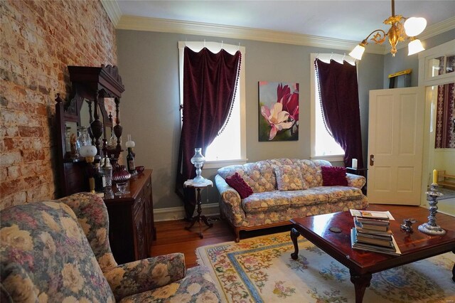 living room with brick wall, ornamental molding, a chandelier, and hardwood / wood-style floors