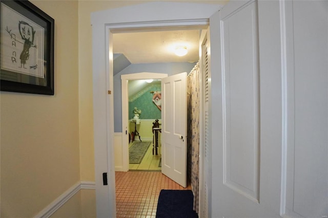 hall featuring vaulted ceiling and light tile patterned flooring