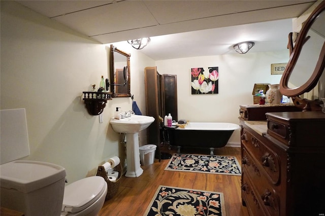 bathroom with hardwood / wood-style flooring, toilet, sink, and a washtub