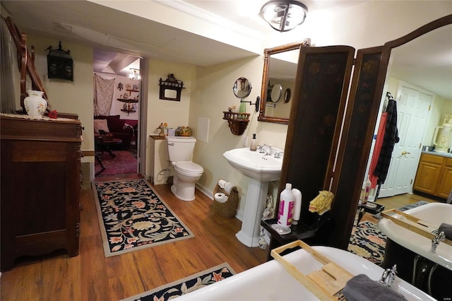 bathroom with wood-type flooring, toilet, sink, and a bath