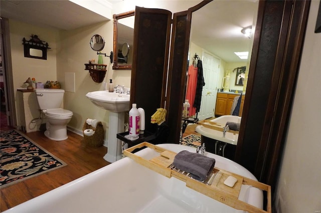 bathroom featuring hardwood / wood-style flooring, toilet, a bathing tub, and sink